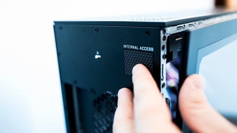 A person pushes on the internal access button on the rear of the PC