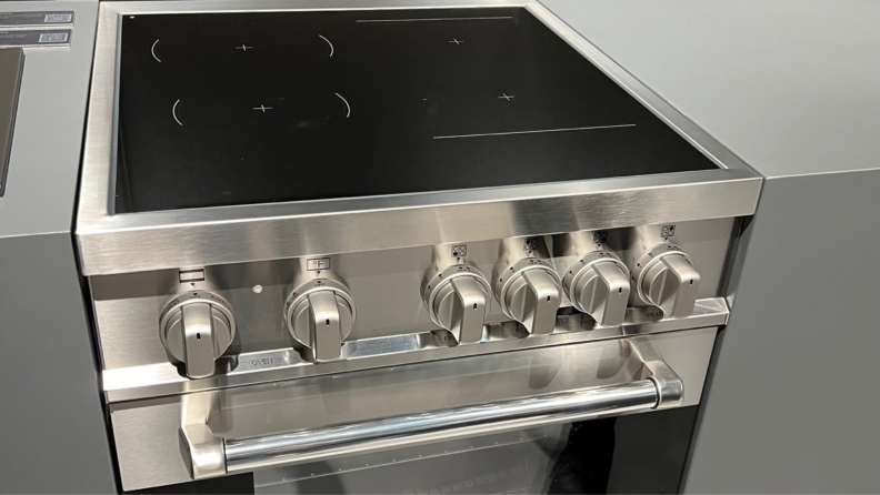 Close-up angled view of the front of the Bertazzoni 24-inch Professional Series Induction range in silver with black stovetop.