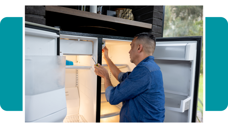 Repair man fixing the interior of a double door refrigerator.