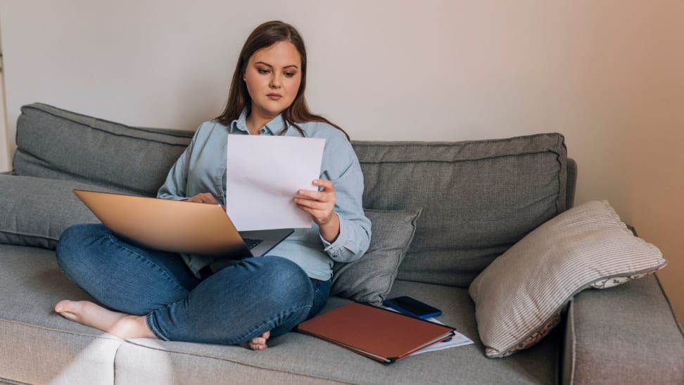 Person holding a piece of paper as they sit on a couch