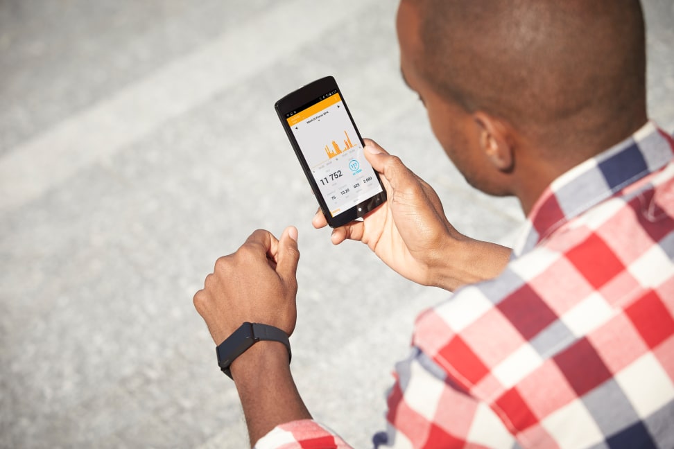 A man wearing the Withings Pulse O2 and looking at the Health Mate app