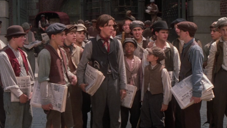 A still from 'Newsies' featuring Christian Bale standing in front of the other newsies.