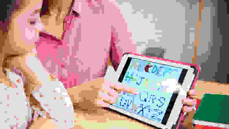 Parent teaching child alphabet with tablet