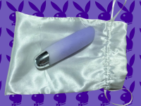 Playboy vibrator on a silk bag on a purple background