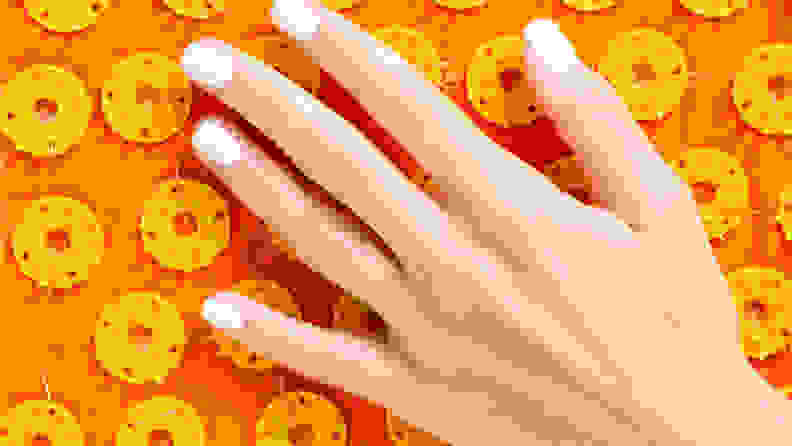 Hand touching orange acupressure mat.