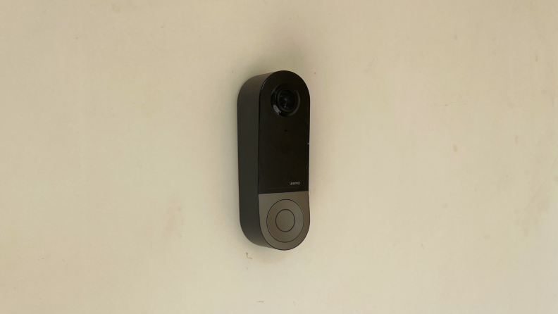 The Wemo Smart Video Doorbell, the best doorbell camera for HomeKit,  hangs on a white door.