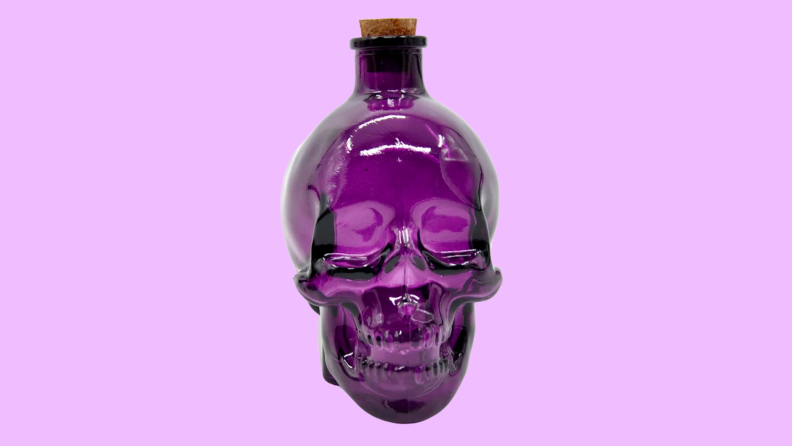 An image of a purple glass skull bottle with a cork stopper.