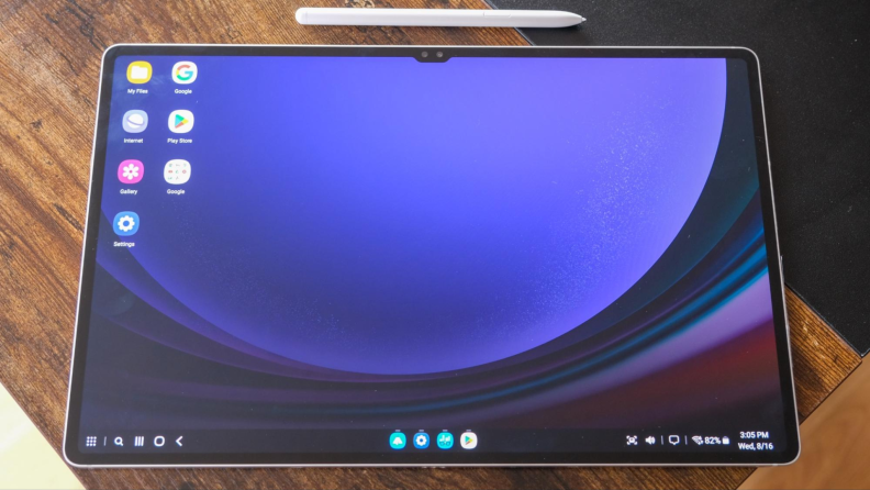 Samsung Galaxy Tab S9 Ultra tablet with desktop display on LED screen next to white S stylus pen on top of wooden surface.