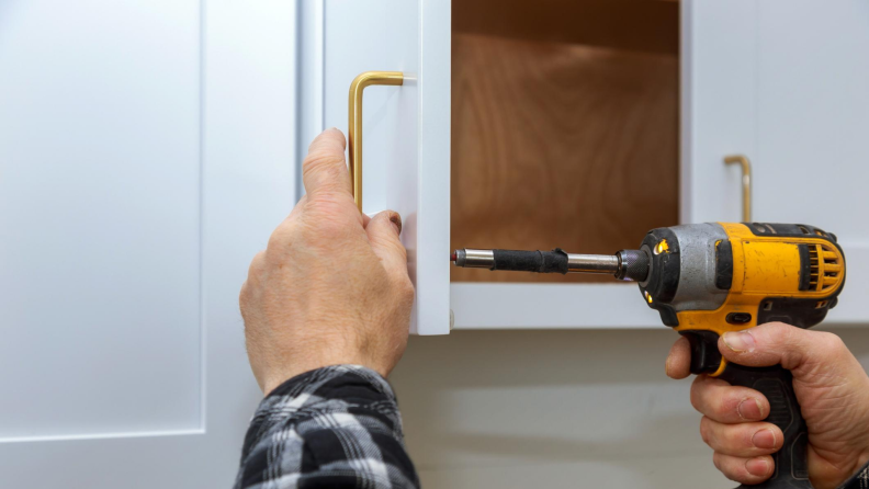 Man installing a new cabinet knob with a drill