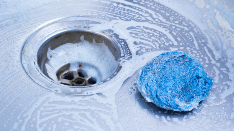 A ball of steel wool sits in a stainless steel sink.