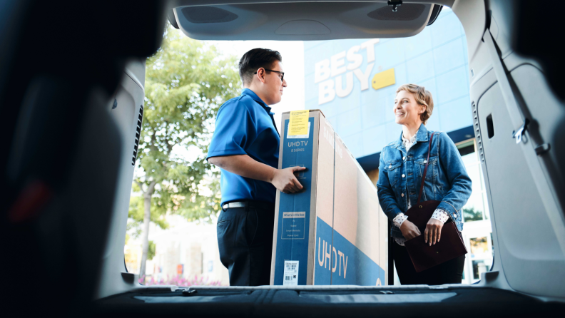 Man helping woman load a TV into a car