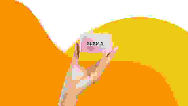 Hand holding up jar of Elemis face cream.