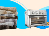 A stack of towels and a stainless steel toaster oven against a blue background.