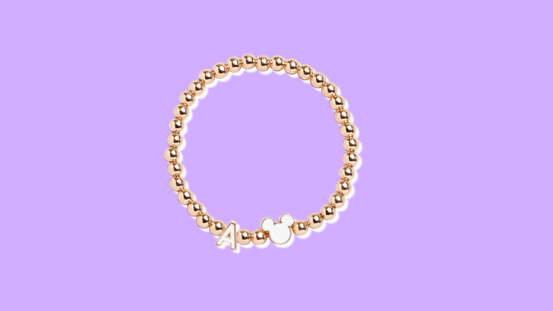 A rose gold beaded bracelet featuring an "A" initial charm and a silhouetted Mickey Mouse head.