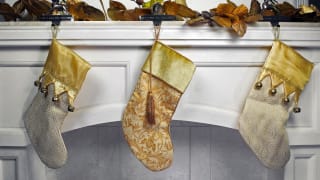 Gold and silver Christmas stockings hanging on a white mantle.