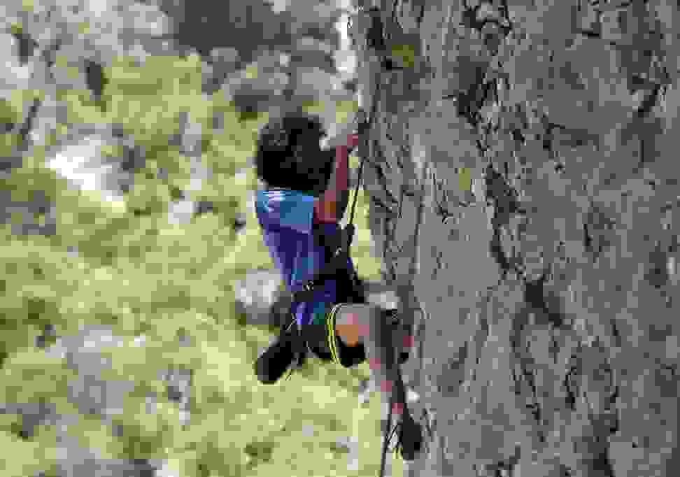 A person climbing a rock wall with climbing shoes and a harness.