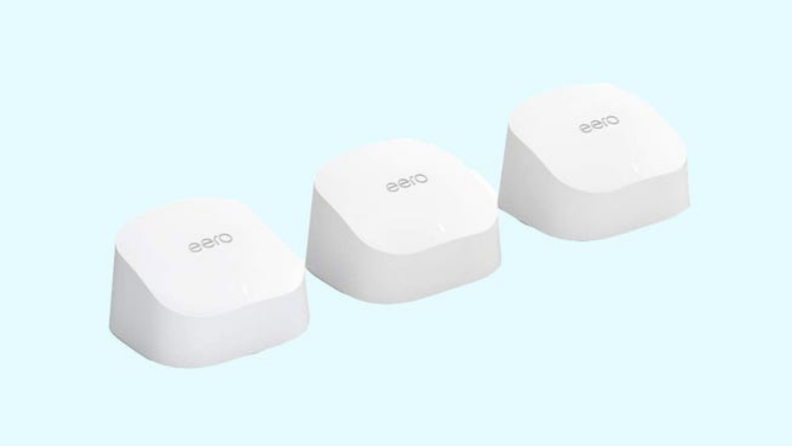 Three white Amazon Eero mesh wi-fi systems lined up next to each other in front of blue background