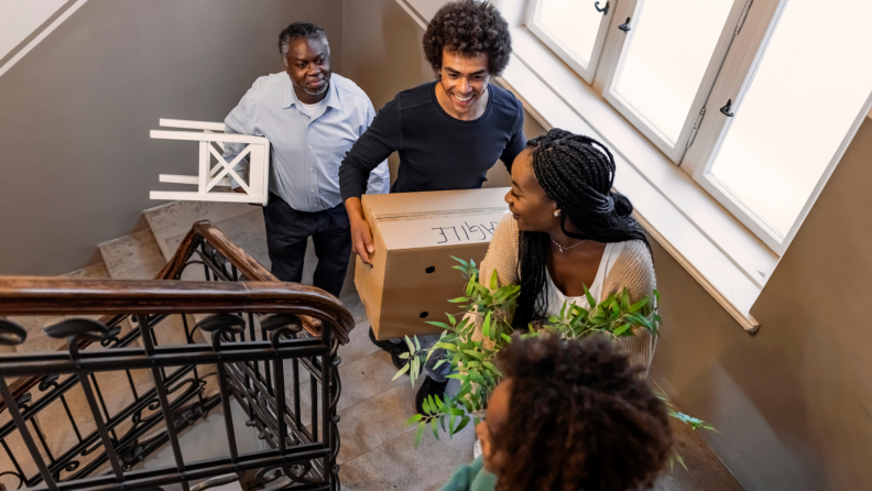 A family carrying boxes up a set of stairs.