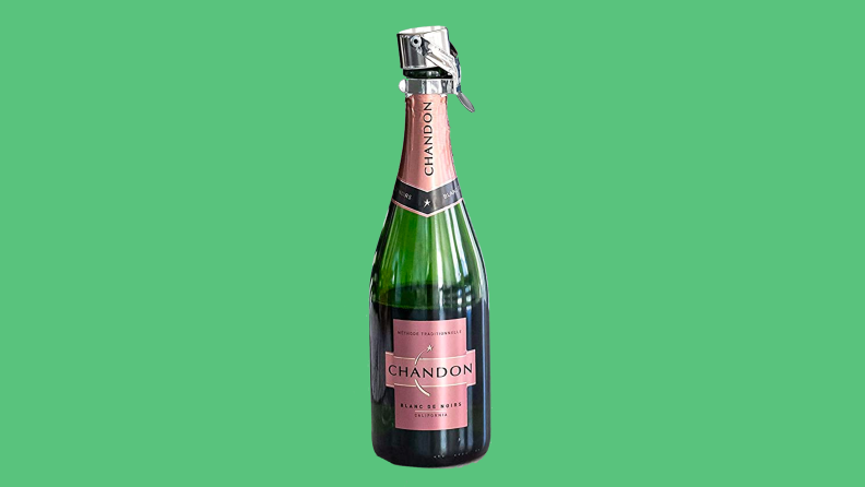 Bottle of champagne with champagne stopper on green background