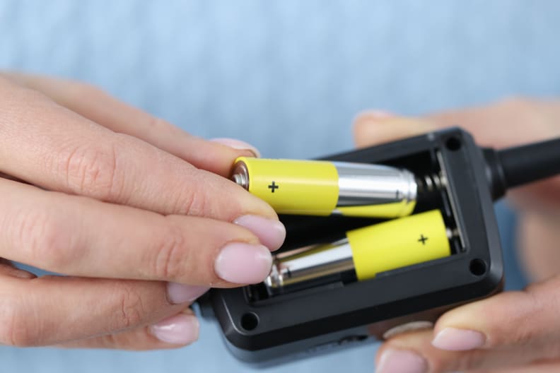 Female hands inserting batteries into remote closeup. Repair of household appliances concept