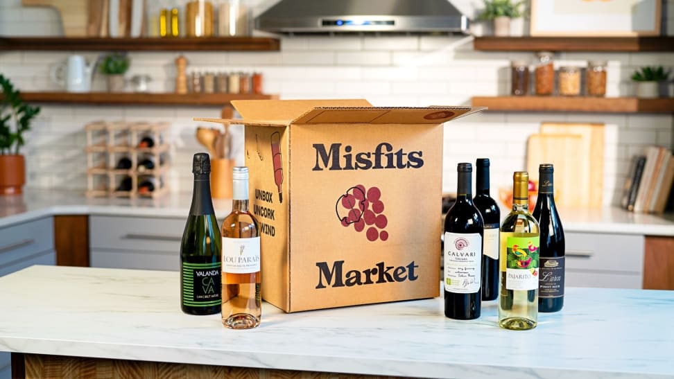 A Misfits Market open box sitting on a marble countertop surrounded by  wine bottles