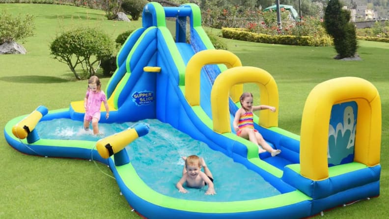 Kids playing outdoors on blue, yellow, and green Bountech Long Slide Bouncer Park.