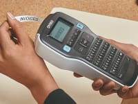 A woman using a label maker to organize her work files.