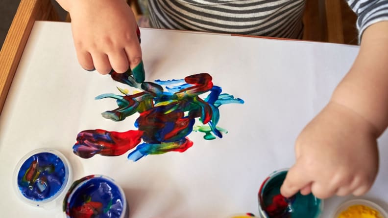 A child's hands finger paint.