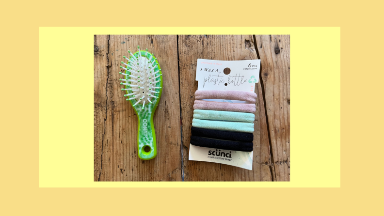 Green plastic hair brush next to Scunci Earth-Friendly Ponytailers on wooden table-top.