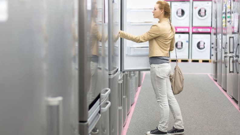 A woman peruses fridges for sale in a big box store