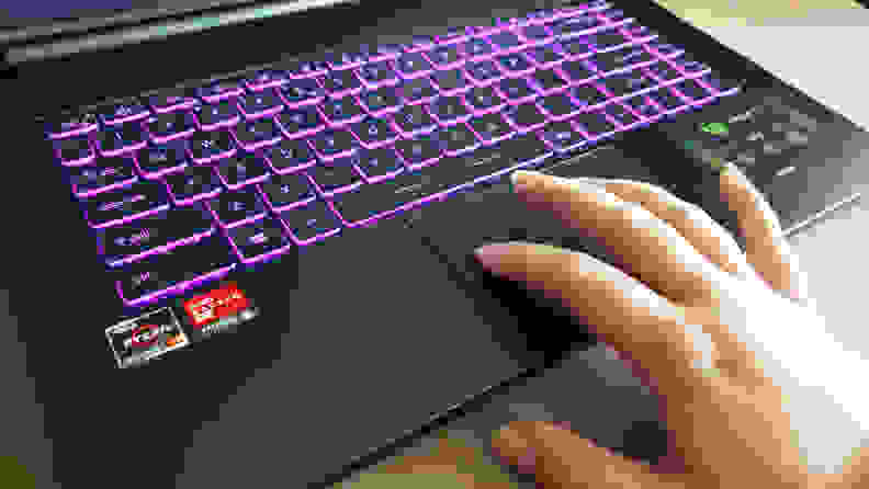 A hand touching a laptop's trackpad