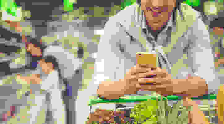 Man grocery shopping use phone