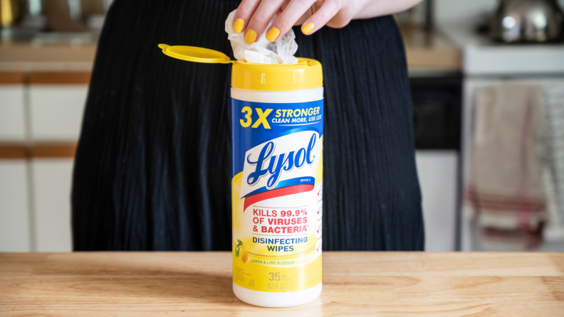 Person reaching for wipe from Lysol disinfecting wipe bottle
