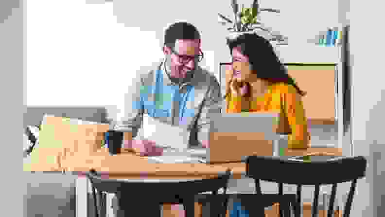 A man and woman look over documents as they sit at kitchen table