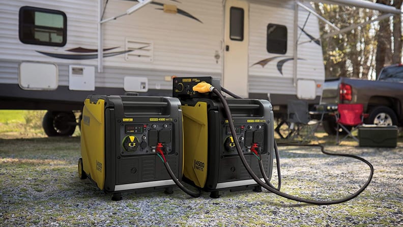 An inverter generator sitting on the ground outside an RV.