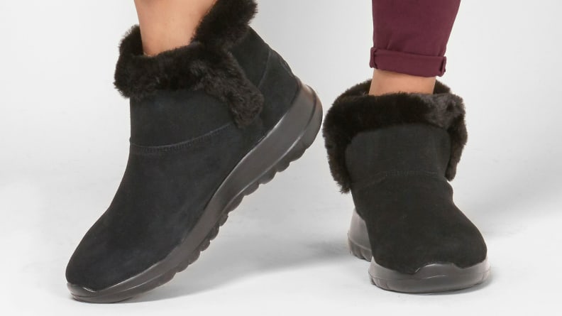 Black fur boots on pair of feet