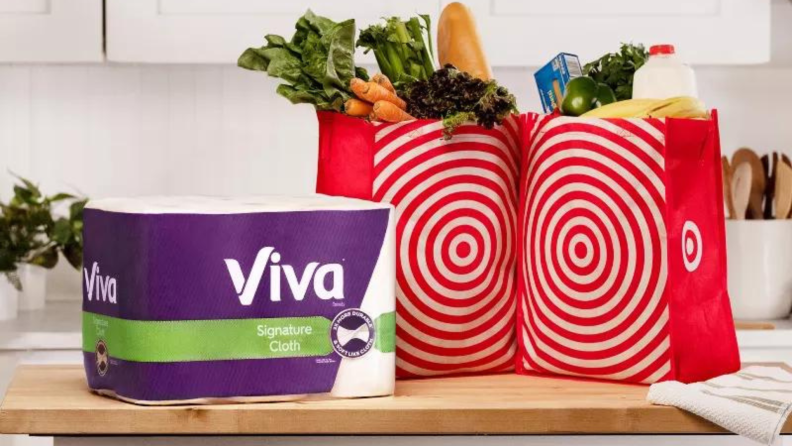 A pack of Viva paper towels on a kitchen counter next to shopping bags.
