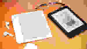 Two e-readers sitting on a wooden surface with a pair of glasses