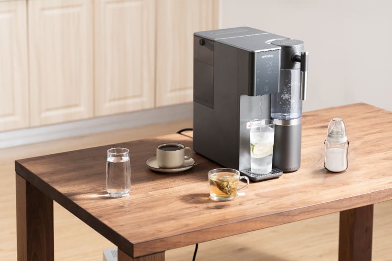Black Waterdrop A2 reverse Osmosis system on a wooden table with cups of tea and coffee