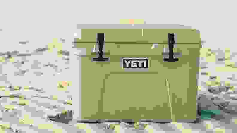 A YETI Tundra 35 cooler with 35-liter capacity is seen either on a sandy beach or in the middle of a dessert.