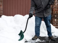 A person shoveling snow with an ergonomic snow shovel.