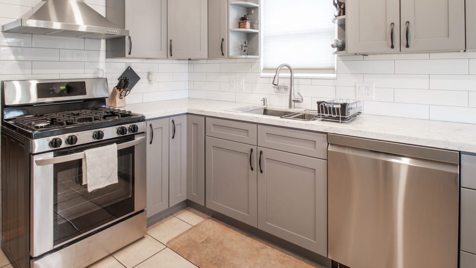 An array of appliances, including an oven, a dishwasher, and a range displayed on tiled floors in a kitchen.