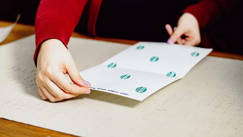 Women sticking sheet to a back of a puzzle