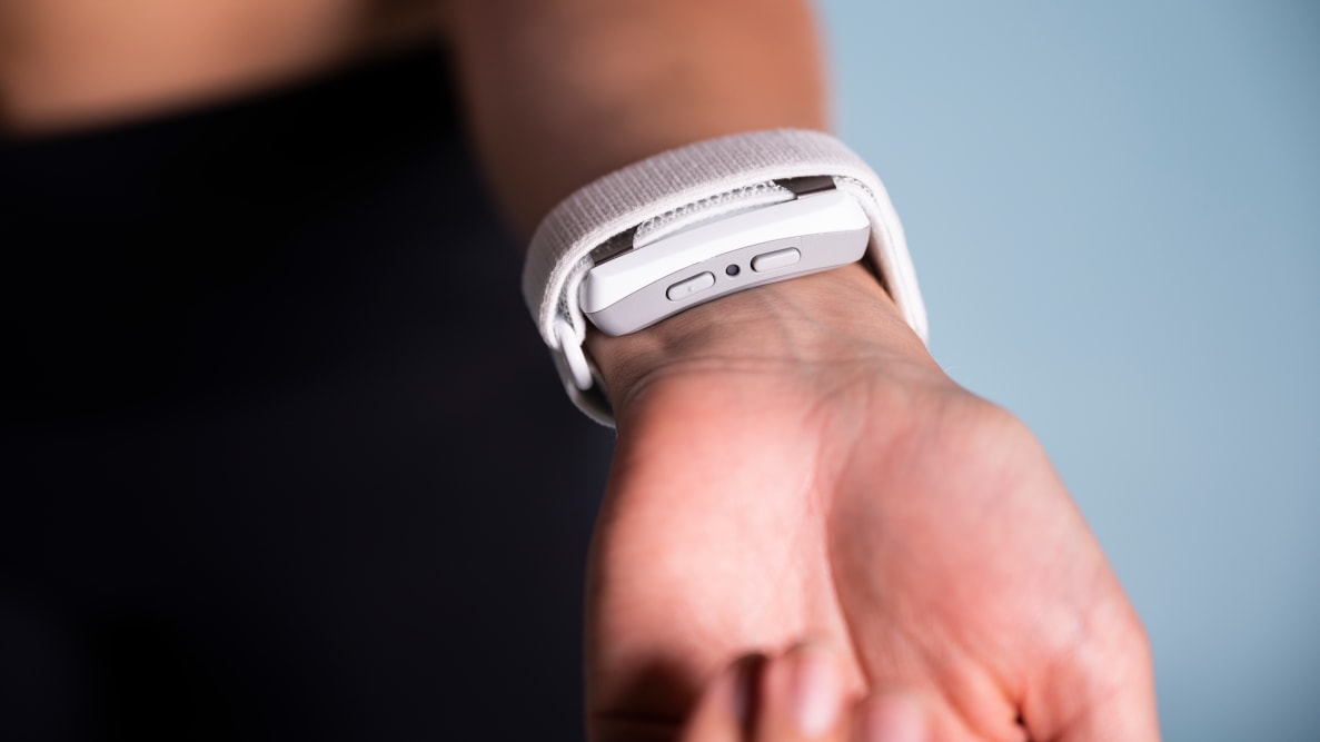 A person wears a white stress relief smart device on their wrist.