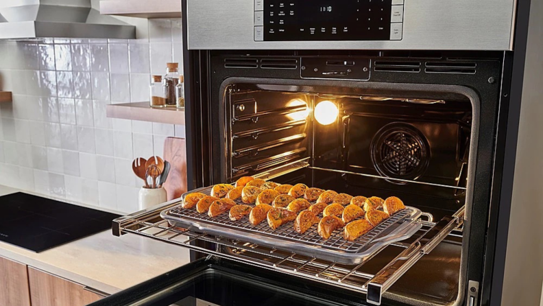 Bosch HBL8454UC oven door open with air fried potatoes on baking sheet on top rack.