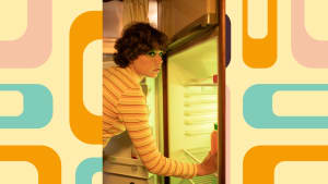 A woman looks guilty reaching into a fridge from the 1970s