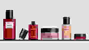 Five makeup, skincare, and fragrance bottles from Chanel sitting on a shelf with a gray background.