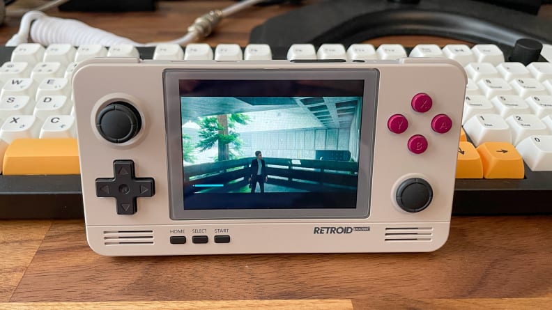 The Retroid 2+ stood up in front of a computer keyboard.