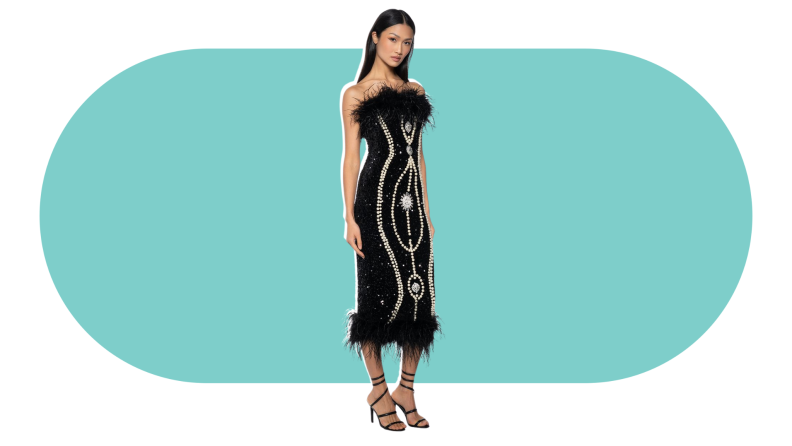 A model wearing a black bodycon dress embellished with beadwork and feathers.
