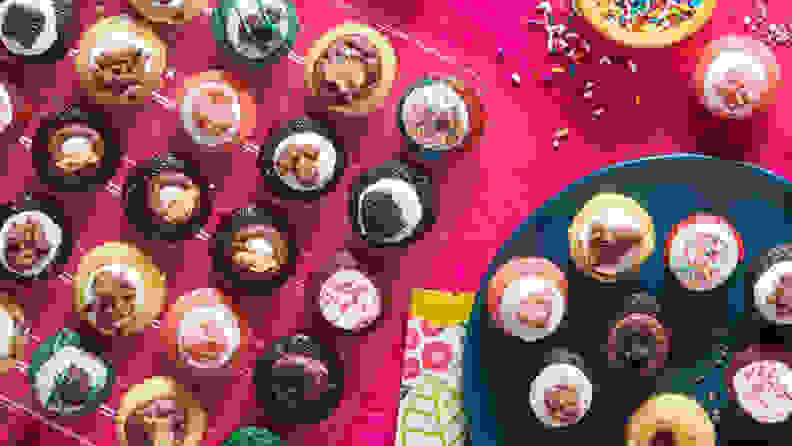 A spread of Baked By Melissa's mini cupcakes on a pink background
